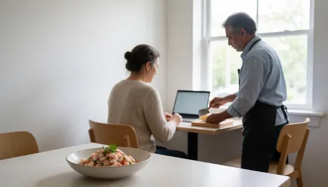 A plate of corvina ceviche sits on a table near a window with natural light while an employee prepares food nearby.