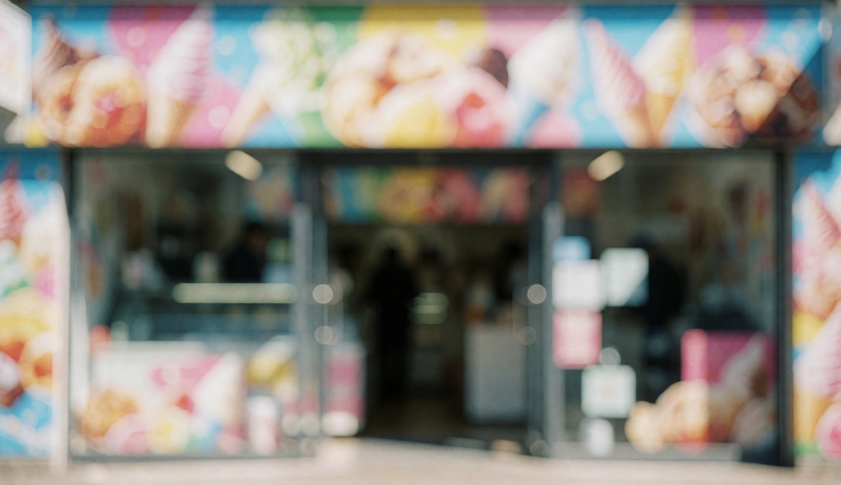 Blurred background of a colorful ice cream shop facade with glass windows, ideal for text overlay.